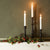 taper candle in white styled with rustic black candlesticks and rose hips 