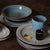 black sake cup and blue mug on stacked plates